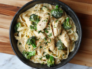 Chicken and broccoli Alfredo without pasta served in a creamy sauce, garnished with fresh herbs in a low-carb, keto-friendly dish.