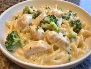 Chicken and broccoli Alfredo without pasta served in a creamy sauce, garnished with fresh herbs in a low-carb, keto-friendly dish.